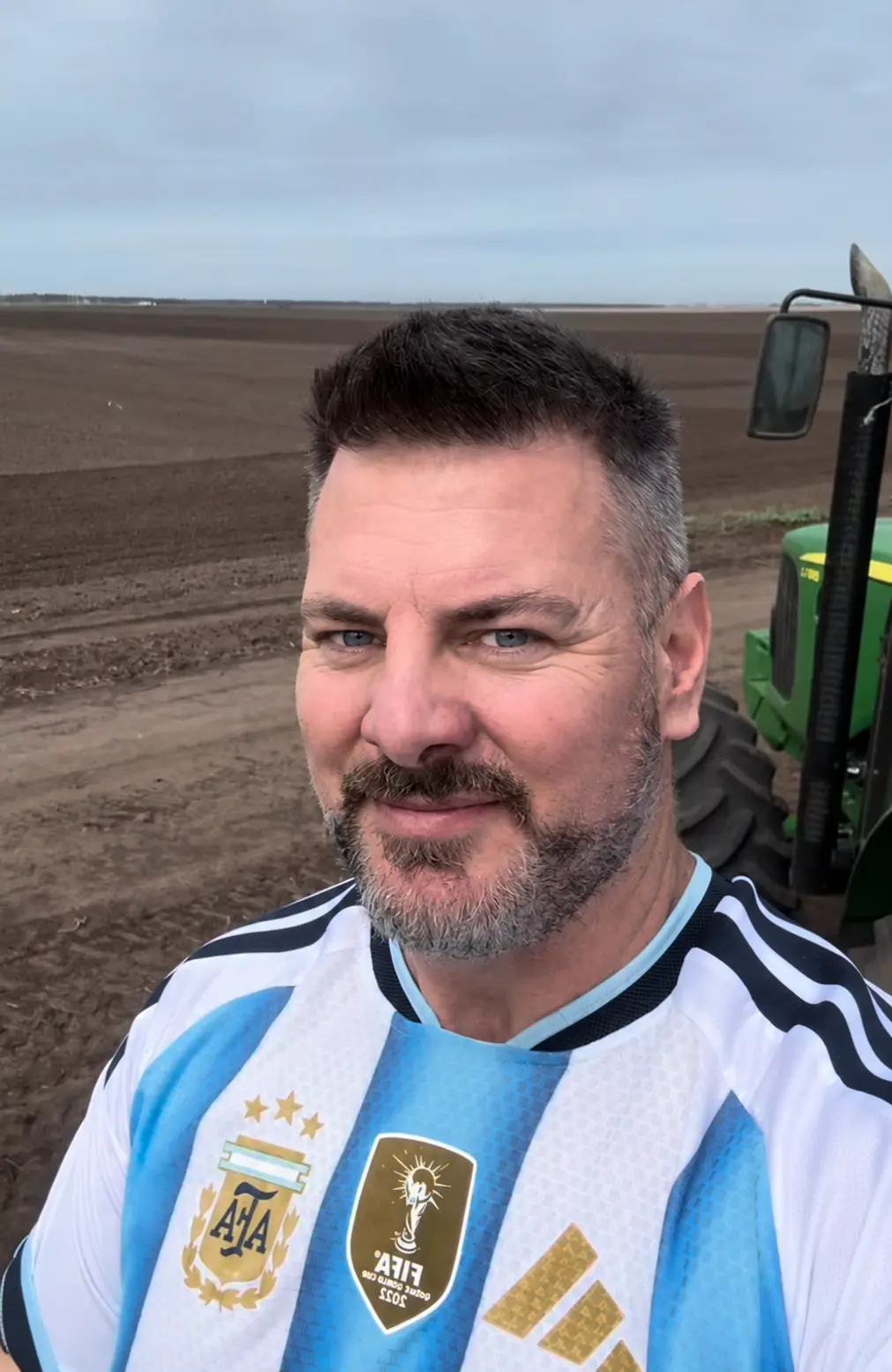 Damián, de Apa la Papa, sonriendo en el lote recién arado junto al tractor