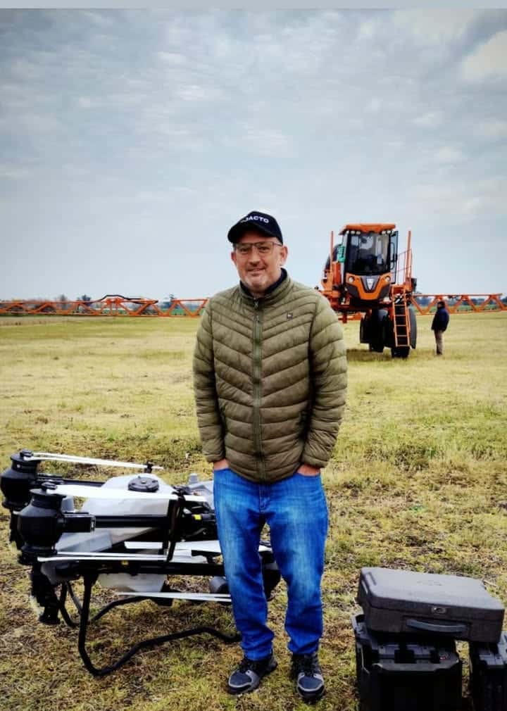 Integrante del equipo junto al drone y la pulverizadora en el campo
